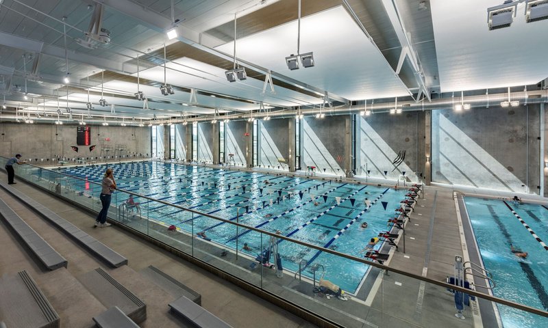 Competition pool viewed from elevated seating with diagonal concrete bracing on the far wall