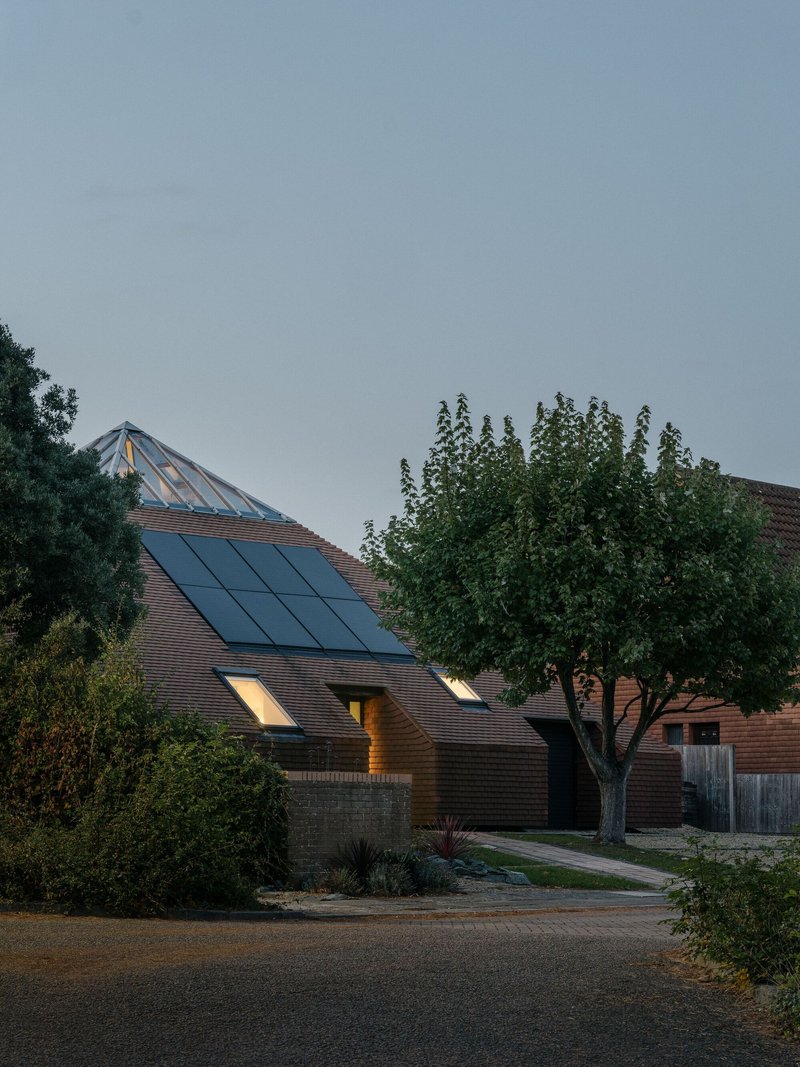 Street view of the tiled roof with integrated solar panels and skylight at dusk