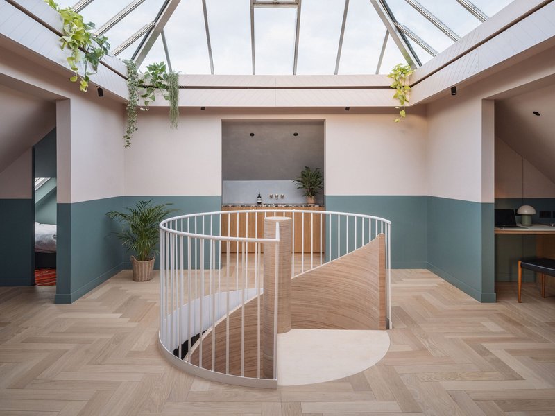 Upper level gallery with glazed skylight roof and curved stair opening with hanging plants