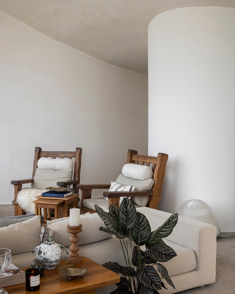 White cylindrical column beside seating area with indoor plant and arched ceiling above