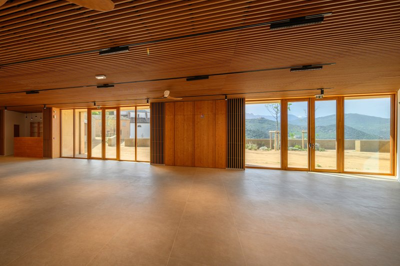 Interior hall with slatted timber ceiling and floor-to-ceiling windows framing distant mountain views