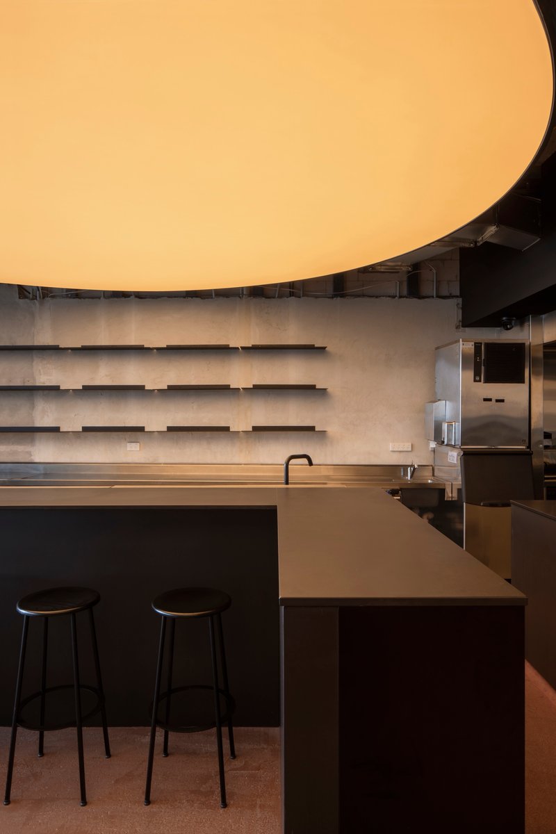 Bar counter detail showing horizontal concrete shelving and curved illuminated ceiling above