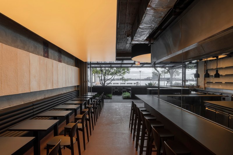 Dining room looking toward floor-to-ceiling windows framing trees and water beyond