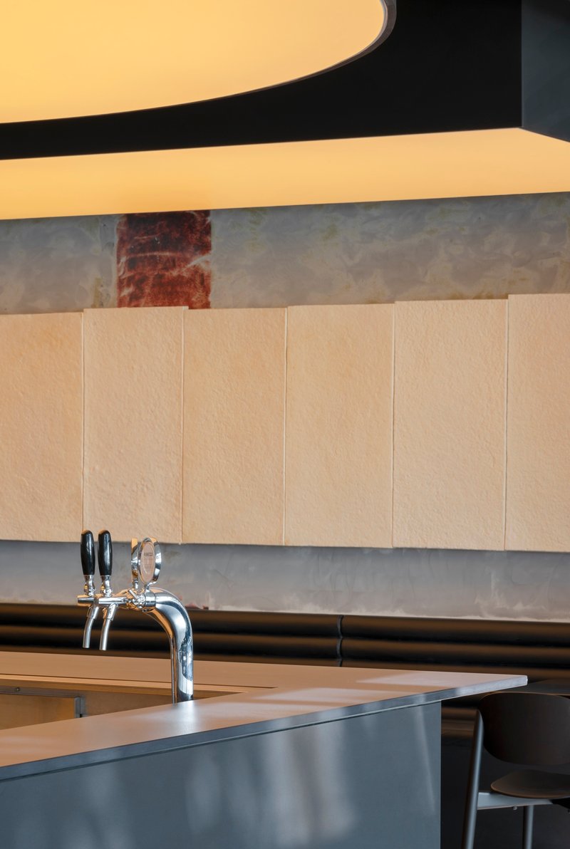 Bar counter with chrome beer taps against a textured metal panel backdrop