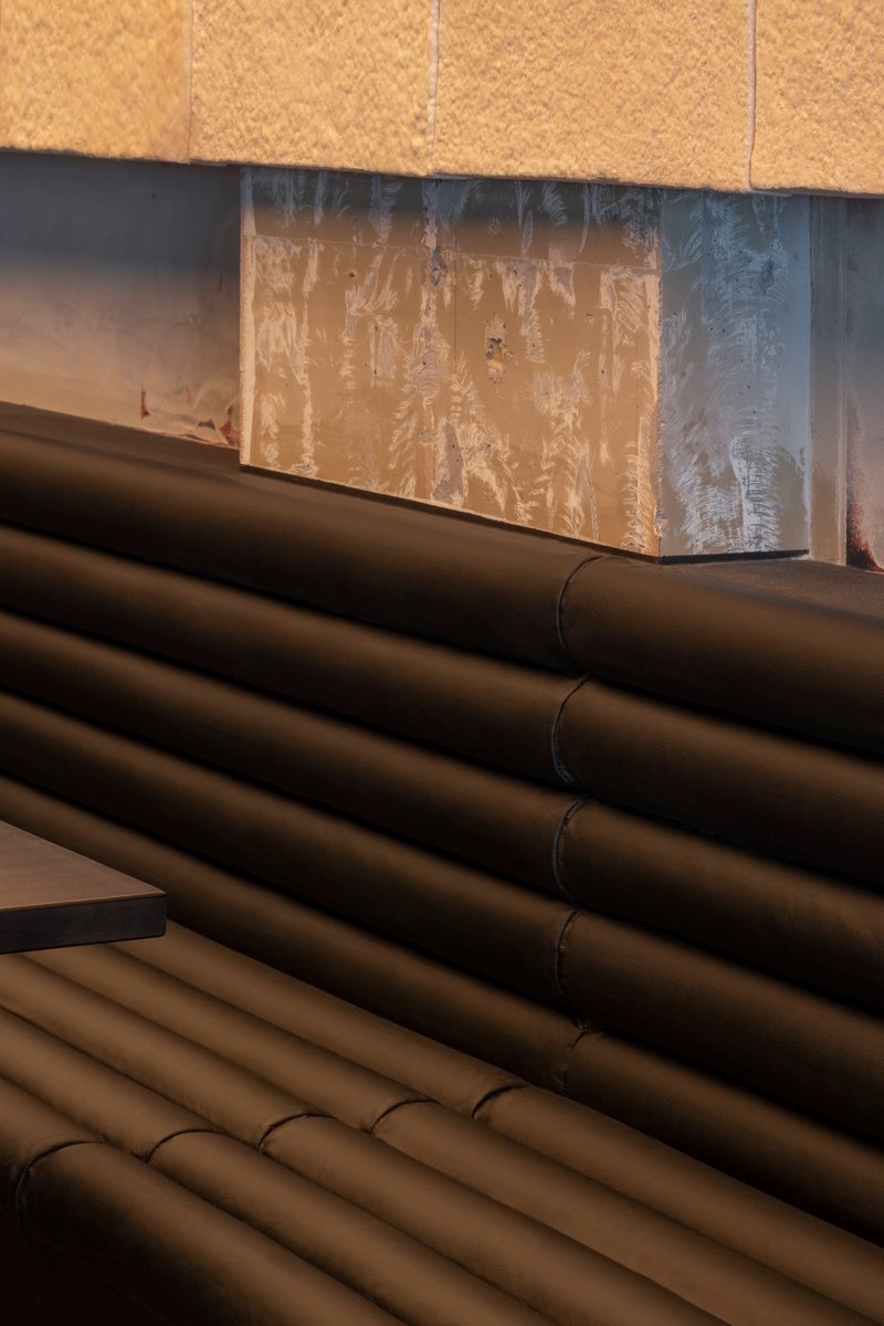Close-up of black cylindrical piping below wood panels and weathered metal surface