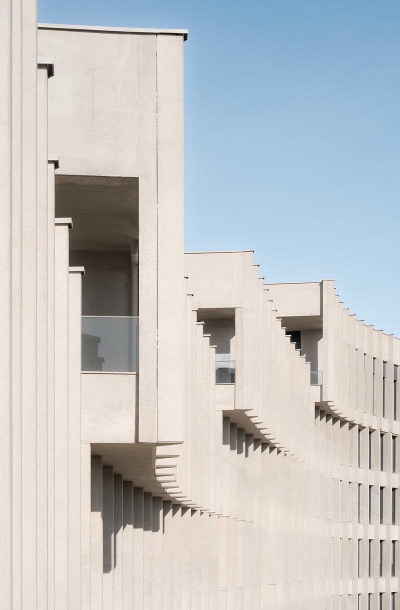 Close-up of the vertically ribbed white facade with recessed balconies casting deep shadows