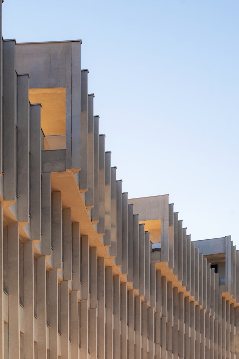 Detail of the stepped vertical fins catching warm evening light against a pale sky