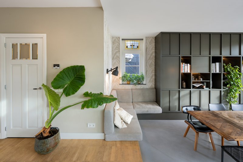 Living space with modular grey shelving wall and potted tropical plant beside a white paneled door