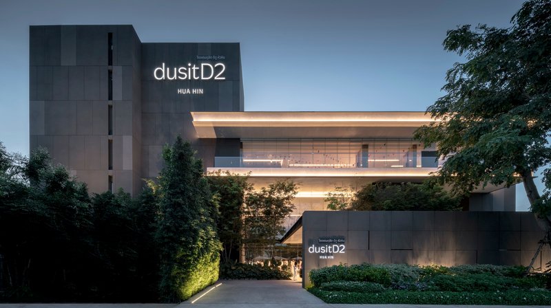 Entry drive approaching the cantilevered horizontal volume with dark vertical tower behind