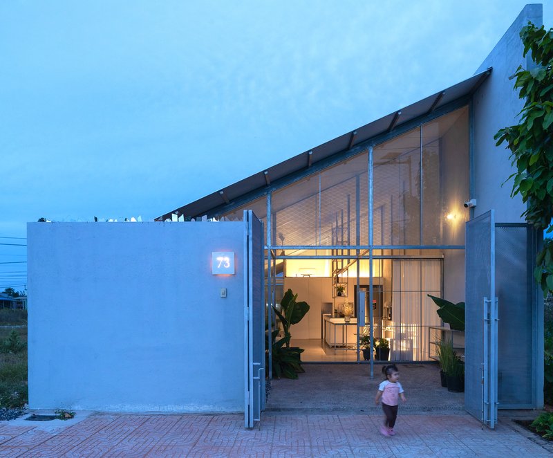 Open entrance gate with child walking through courtyard at twilight
