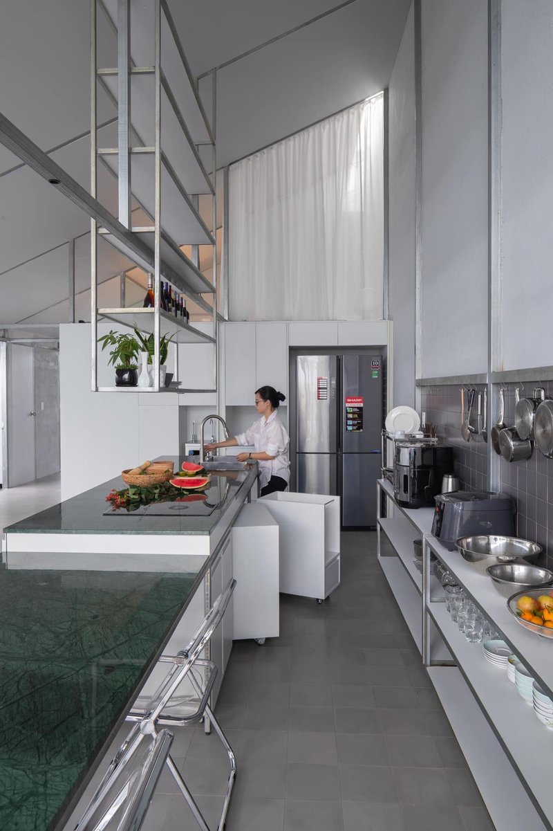 Galley kitchen with open steel shelving and double-height volume visible above white cabinetry