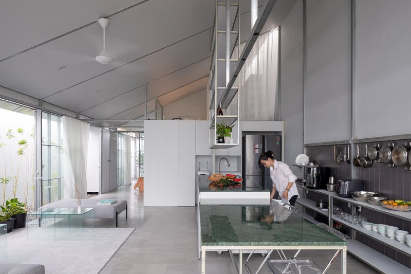 Open-plan kitchen with teal-tiled island and exposed steel ladder stair leading to a mezzanine level