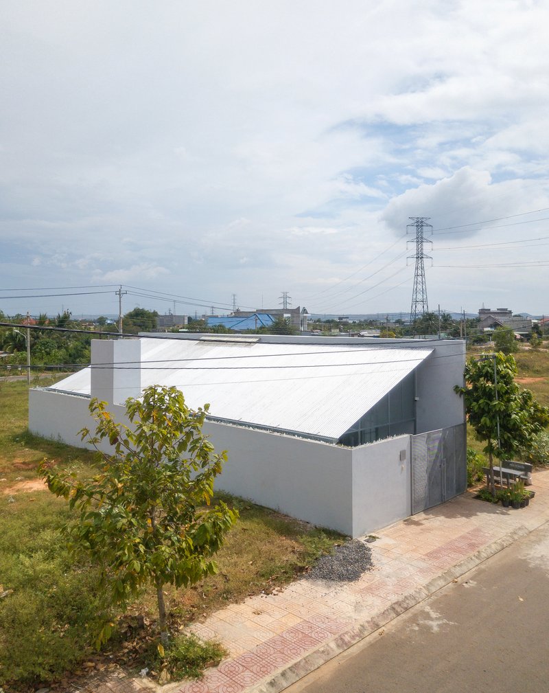Gabled metal roof volume rising above grey masonry walls in a suburban lot with power lines overhead