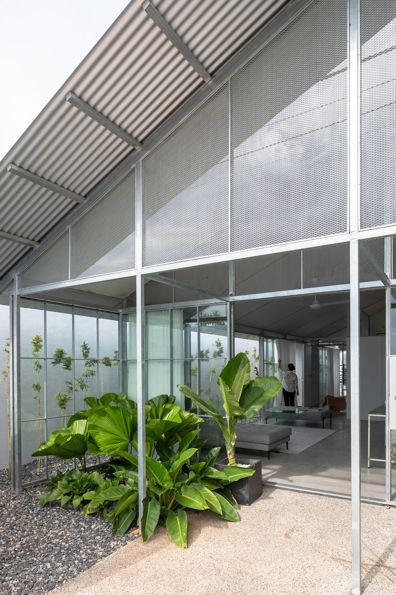 Covered terrace with corrugated metal roof and planted courtyard featuring large tropical banana leaves