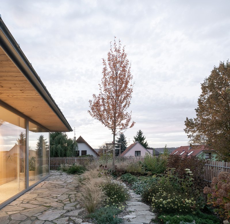 Flagstone patio with planted beds and trees beneath overcast autumn sky at dusk