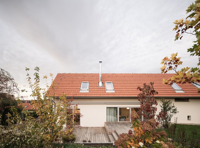 Garden view of the white stucco house with orange clay tile roof and timber deck in autumn