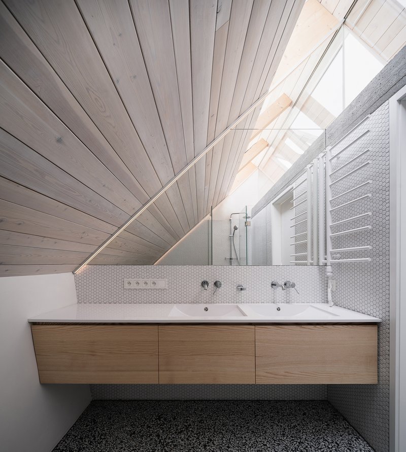 Bathroom with floating timber vanity beneath a white-painted timber ceiling sloping to a skylight