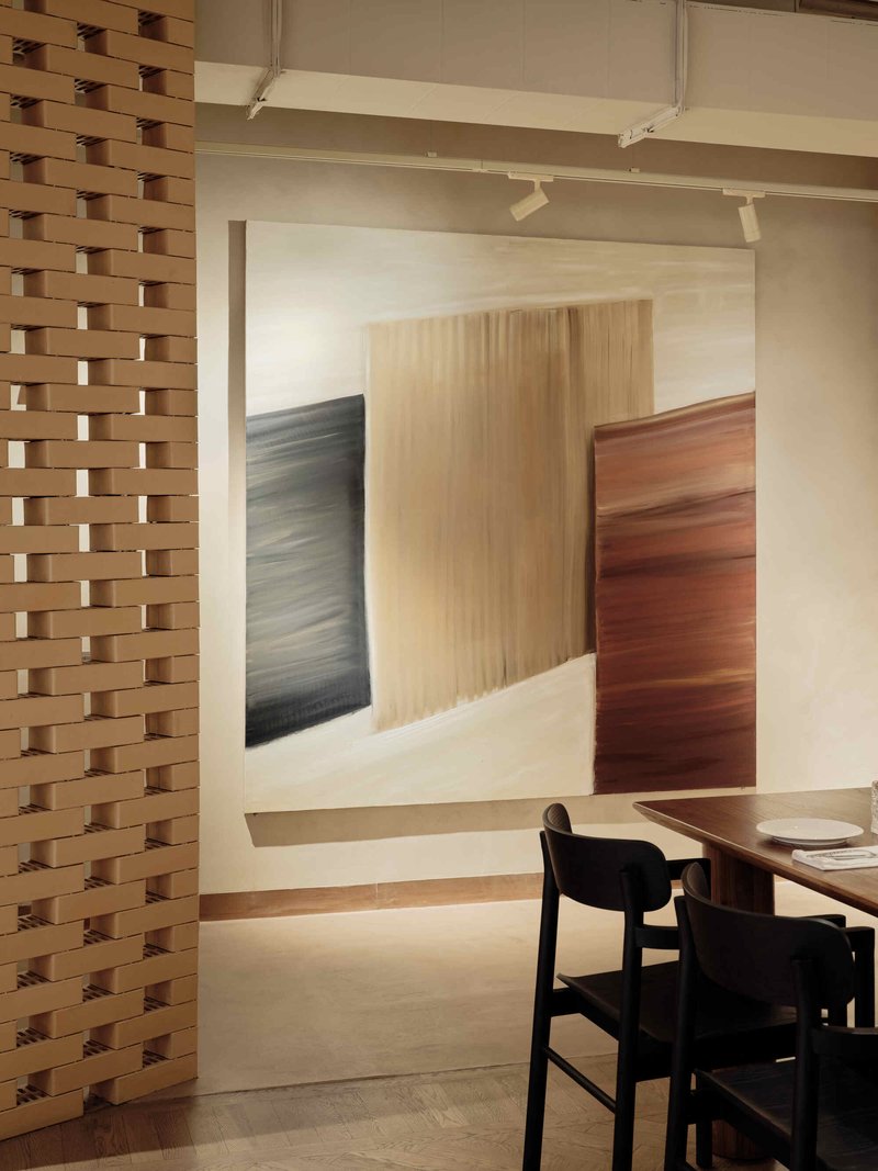 Doorway framed by a basketweave timber screen leading to a dining area with black chairs