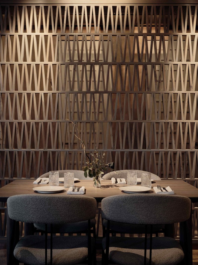 Dining banquette against a latticed timber screen wall with triangular geometric pattern