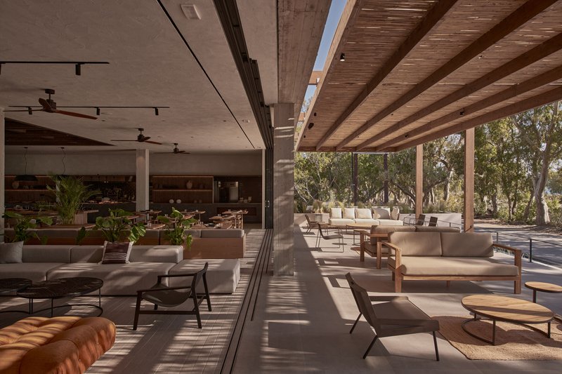 Open living space with concrete columns and exposed timber beams casting diagonal shadows across the floor
