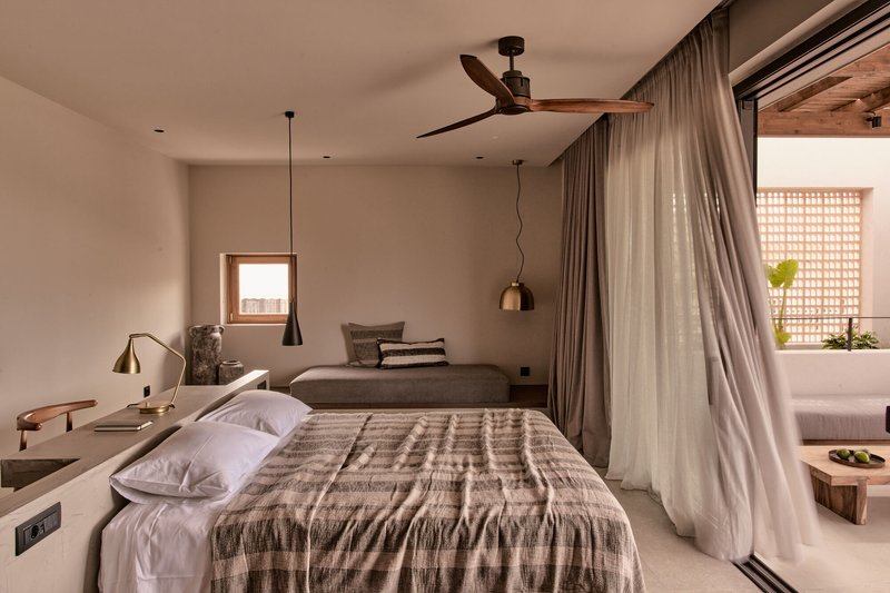 Bedroom with sheer curtains dividing the sleeping area from a sitting nook with lattice screen
