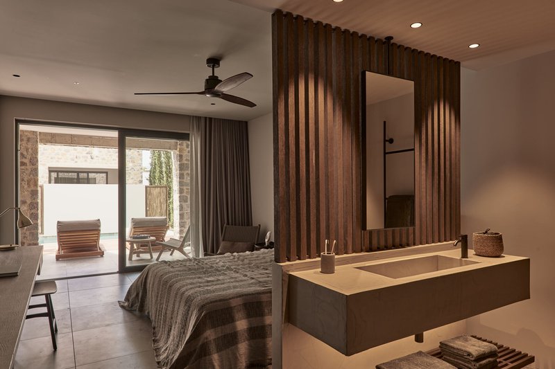 Bedroom with vertical timber slat partition framing a backlit mirror and floating vanity