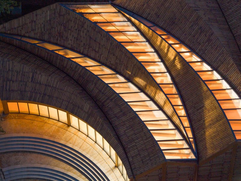 Curved brick vault with illuminated skylights glowing at dusk