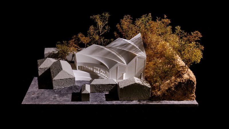 Physical model of the ribbed roof volumes surrounded by miniature trees on a black background