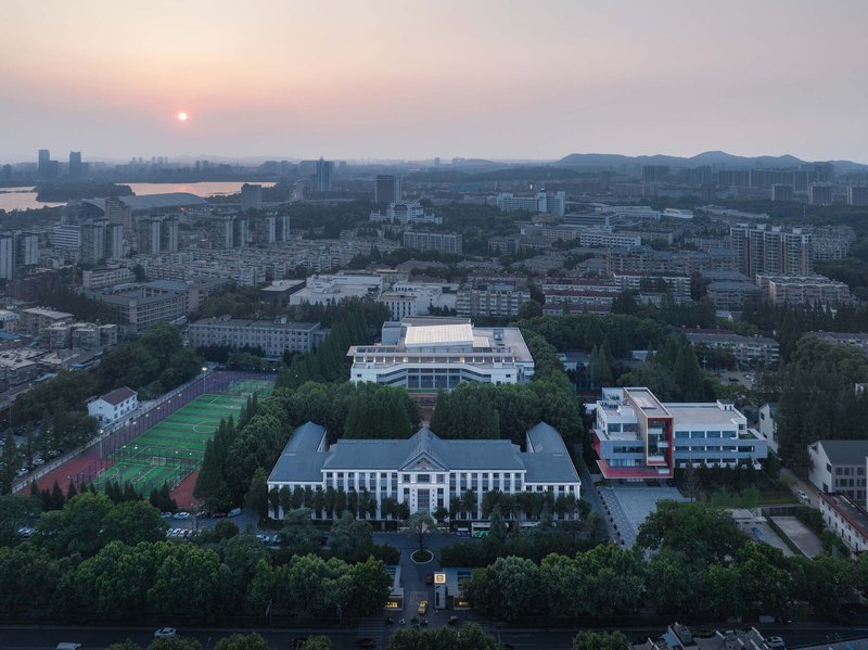 Aerial campus view at sunset showing the original symmetrical building and new tiered library volume