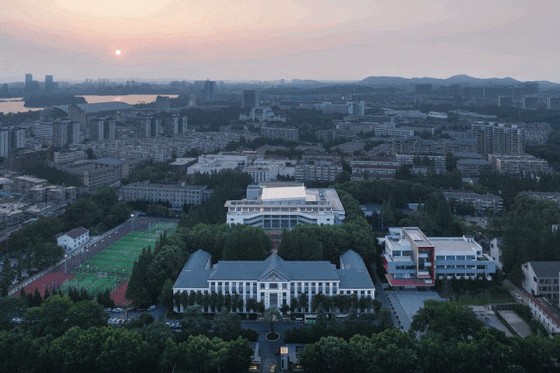Aerial view of campus buildings and playing fields at sunset with distant mountains