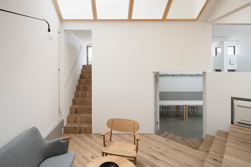 Living area with timber staircase and sliding door opening to a dining space below skylights