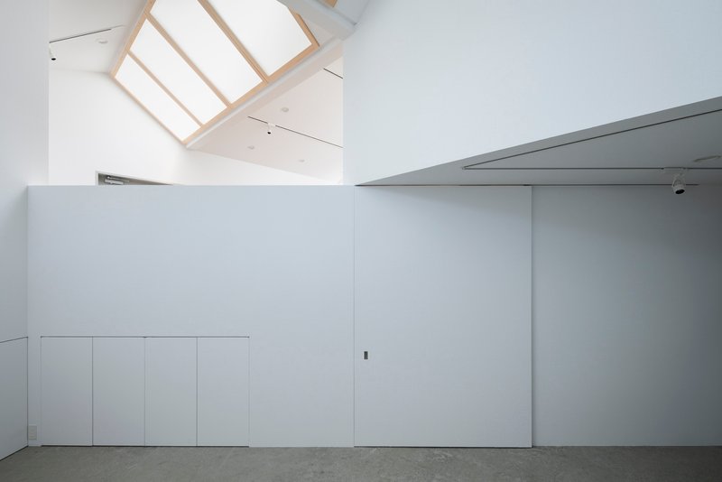 Minimalist white storage wall with polished concrete flooring and recessed ceiling panels
