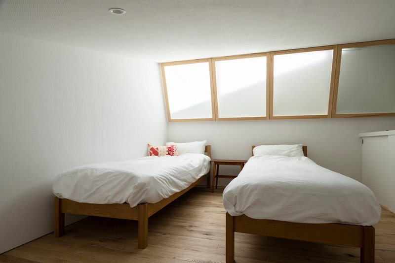Bedroom with two timber beds beneath a ribbon of timber-framed clerestory windows