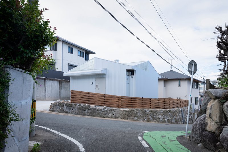 Street view with overhead power lines and timber fence screening the white corrugated metal structure