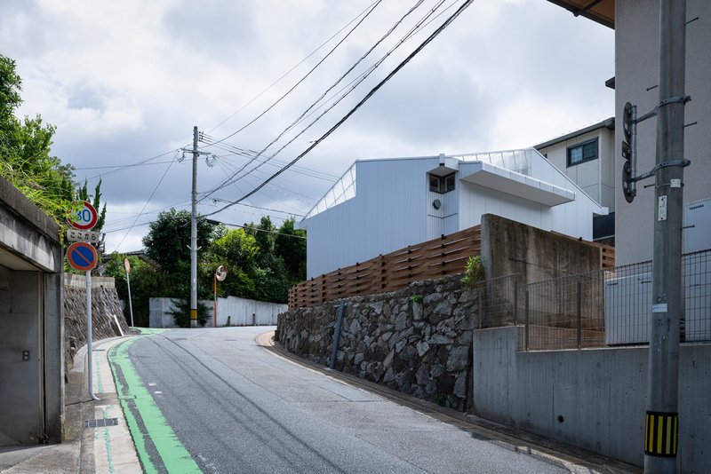Sloping neighborhood street with the house set behind stone and timber boundary walls