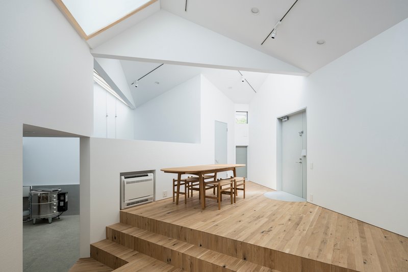 Raised timber platform with dining table and chairs beneath a vaulted ceiling with skylights