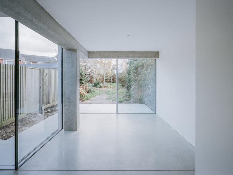 Polished concrete floor meeting perpendicular glazed walls that open onto planted garden pathways