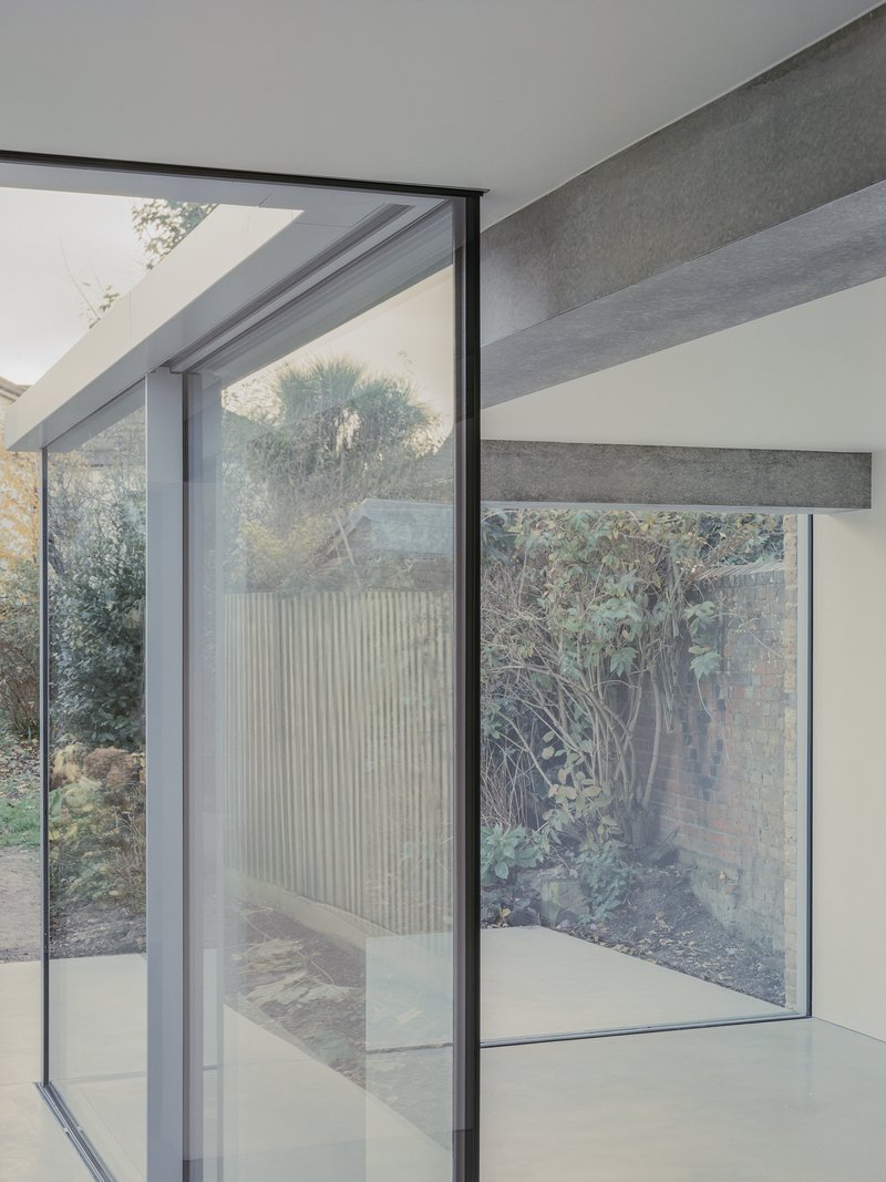 Floor-to-ceiling glazing framing the courtyard with exposed concrete beams and planted garden beyond