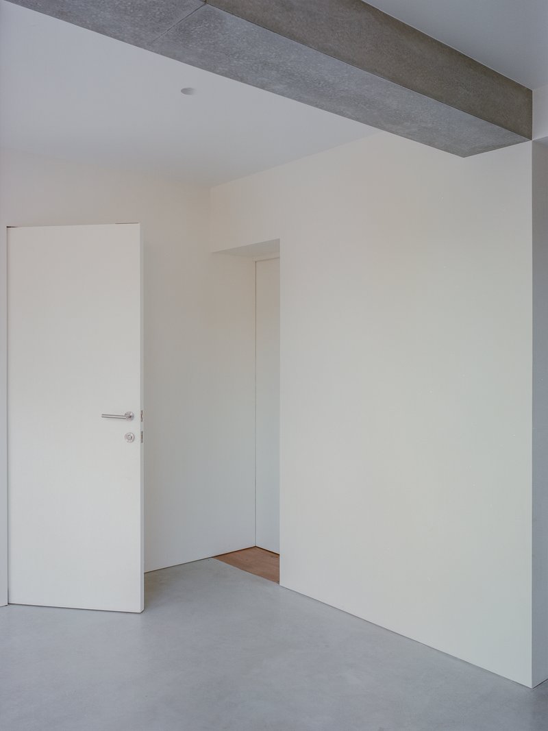 White plastered interior walls with flush doors and exposed concrete ceiling beam