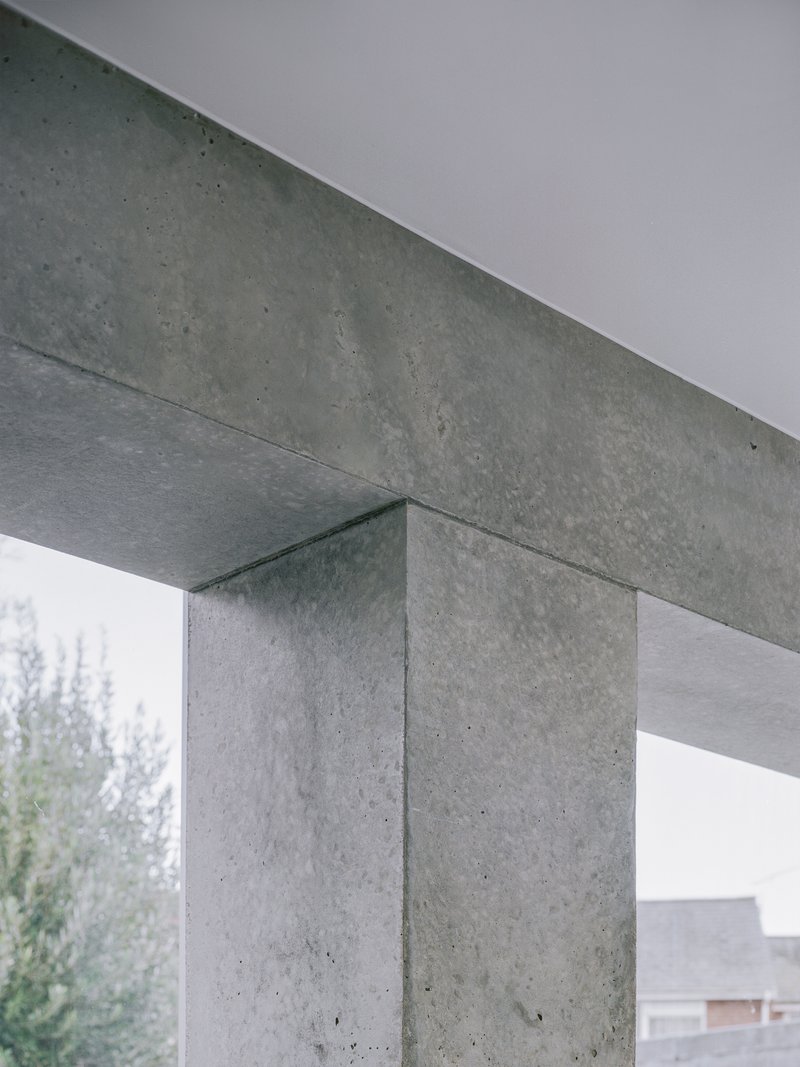 Close-up of concrete beam and column junction with visible formwork texture against overcast sky