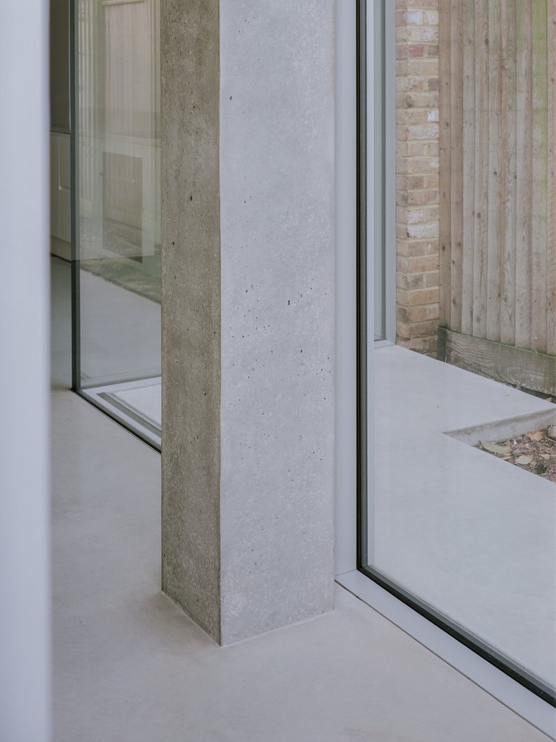 Detail of concrete column meeting glass corner with timber fence and courtyard visible outside