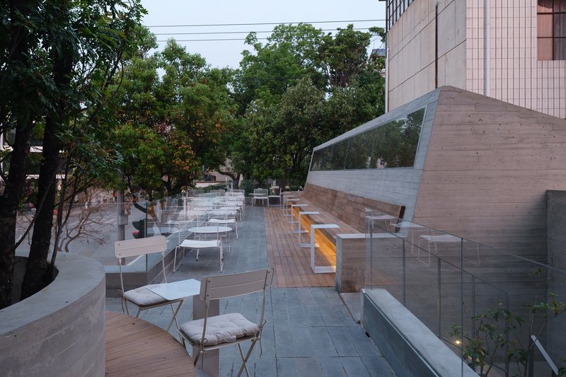 Rooftop terrace with timber decking and glass balustrade overlooking trees at dusk