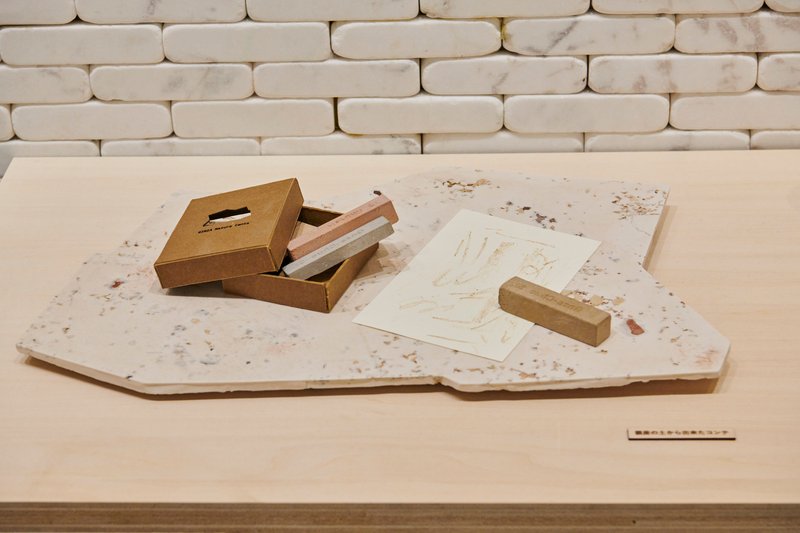 Timber stamp and printed sheet displayed on a terrazzo slab beside an open box with tools