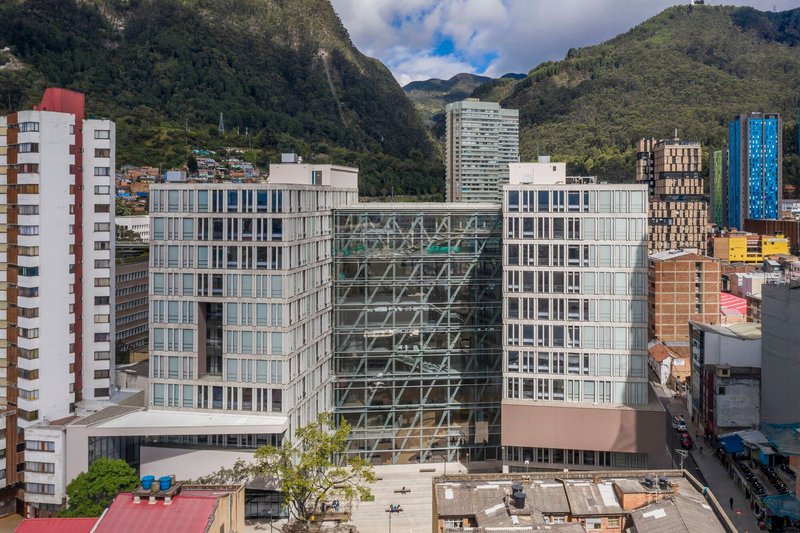 Elevated view of the glass office blocks flanking a central diagrid tower core with green mountains beyond
