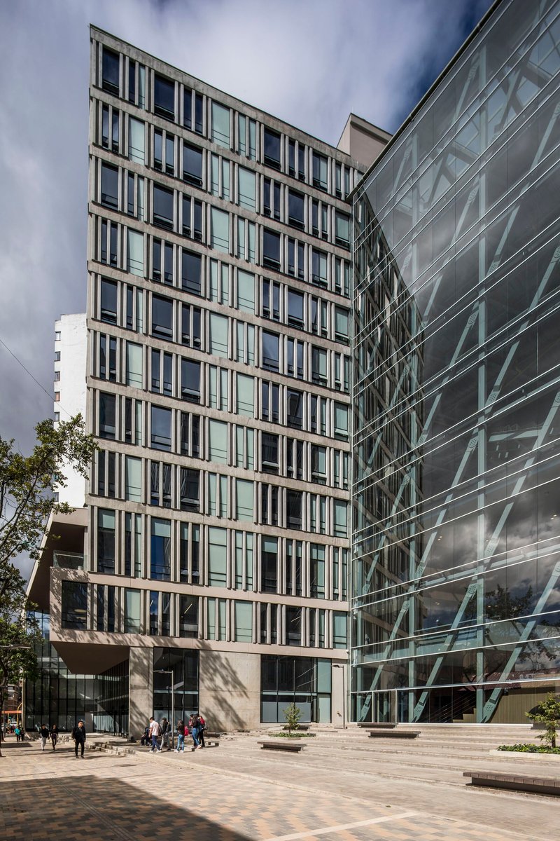 Corner view of the vertical window grid facade meeting the glass curtain wall under cloudy skies