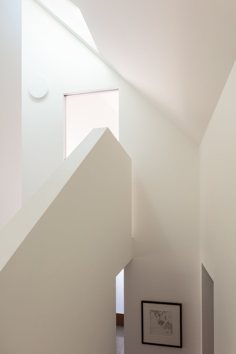 White stairwell with angled walls and a skylight casting diagonal shadows
