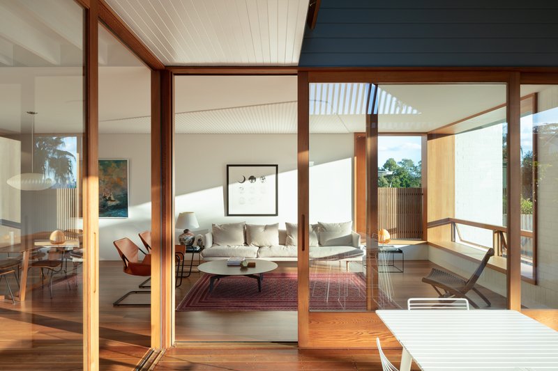 Timber-framed glazed doors opening from deck to living room with beadboard ceiling in afternoon light