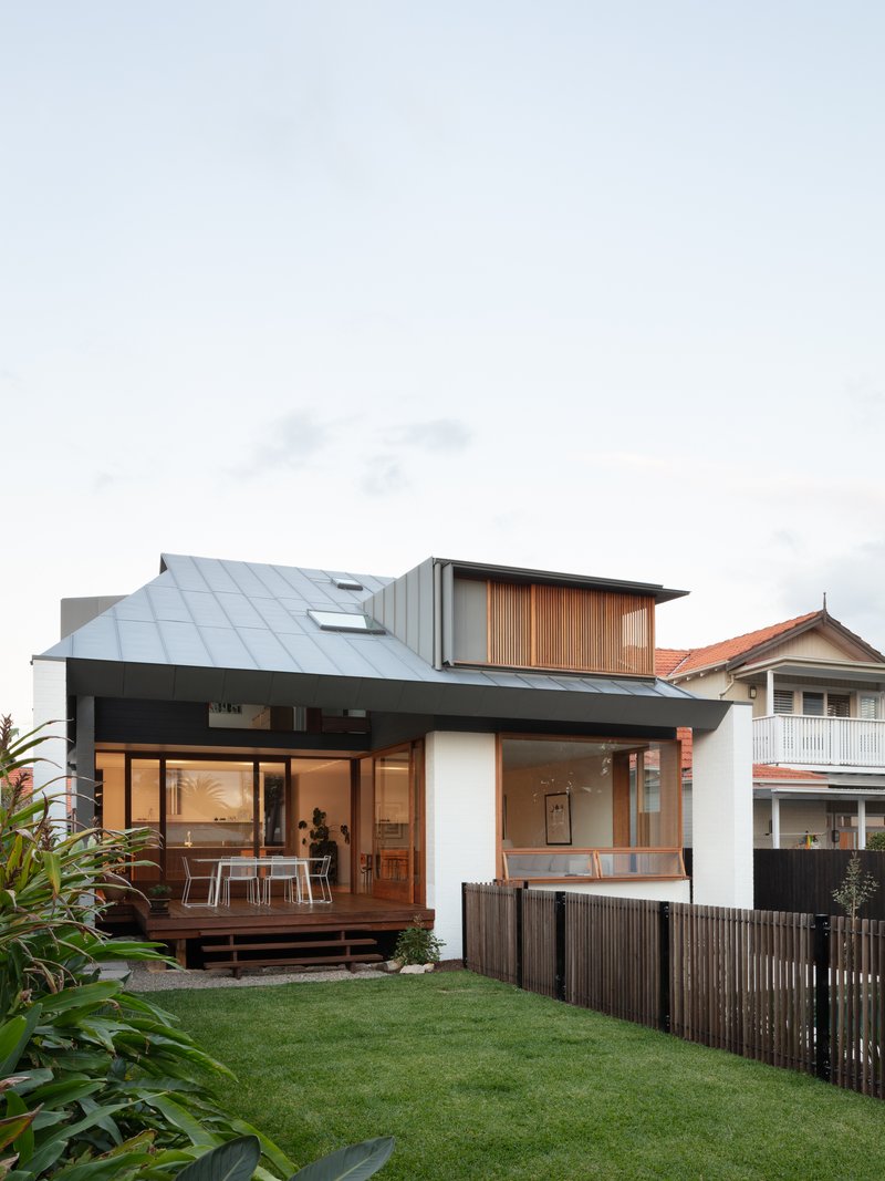 Street view showing sloped metal roof and timber upper volume above landscaped yard