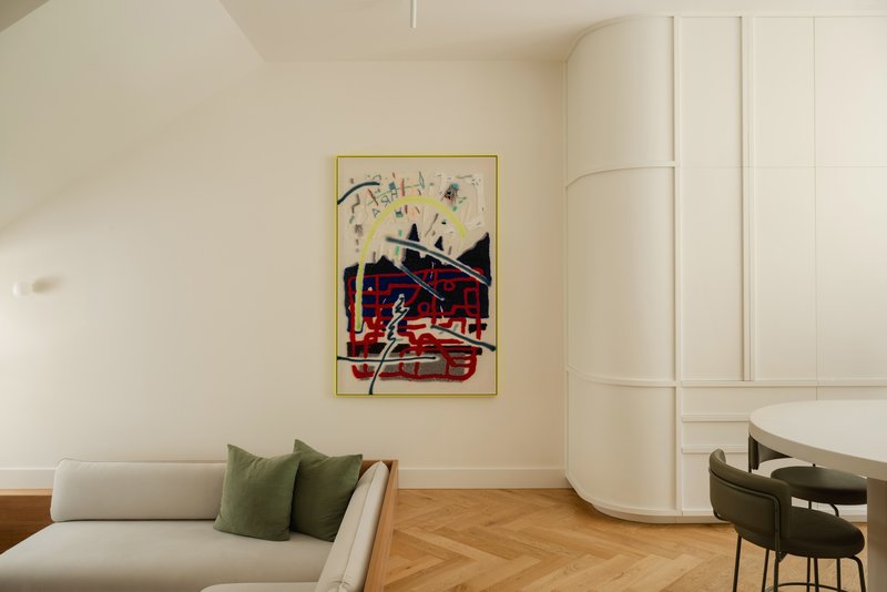 Living area with curved white storage wall and framed abstract artwork above timber herringbone floor