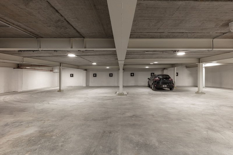 Underground parking level with exposed concrete ceiling, white columns, and numbered parking spaces